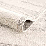 Close up of the Lave Bone Area Rug showing the bone color, subtle stripes, and soft, textured pile. Fold