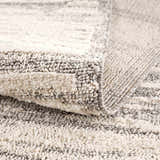 Close-up of the Lave Bone & Taupe Area Rug showing its bone and taupe striped pattern and textured, machine-woven construction. Fold