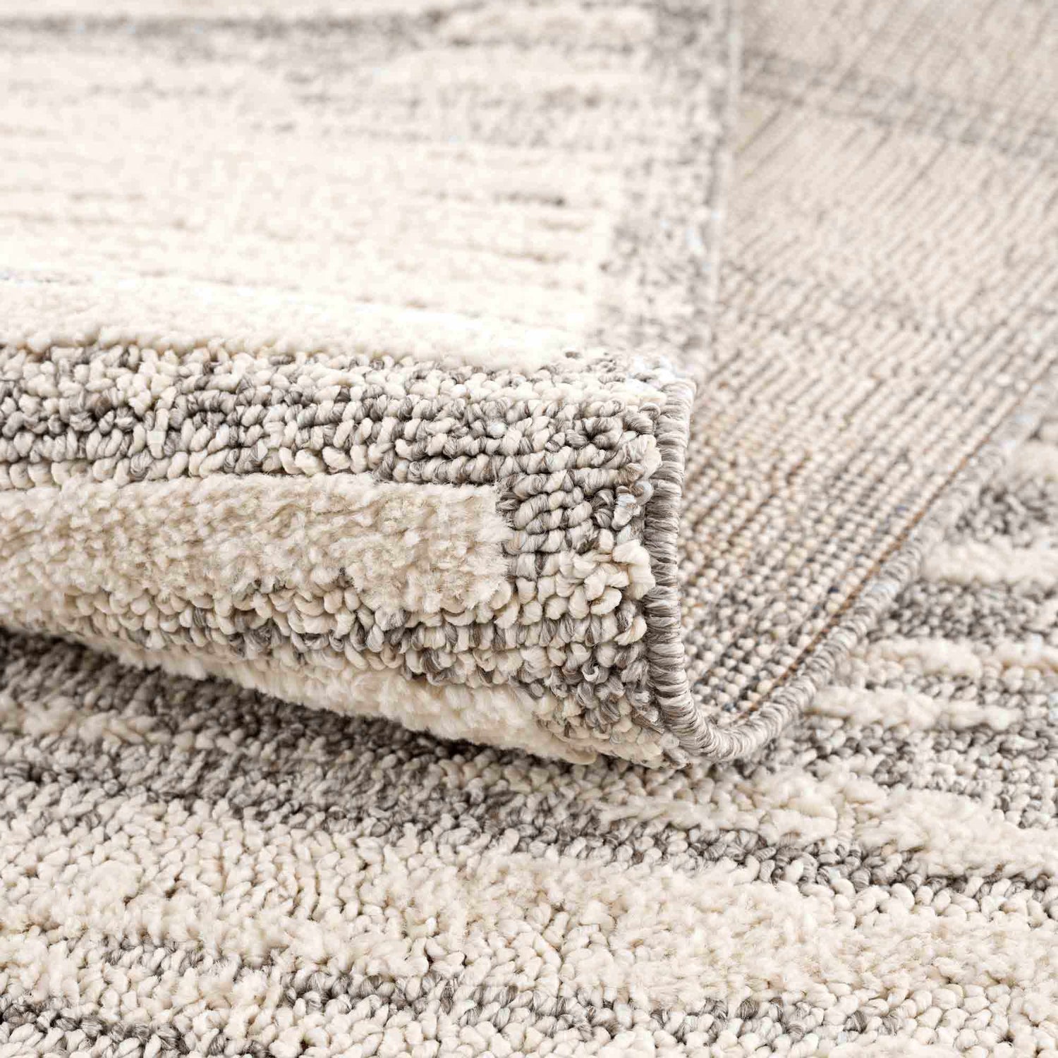 Close-up of the Lave Bone & Taupe Area Rug showing its bone and taupe striped pattern and textured, machine-woven construction. Fold