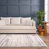 Living room scene with a Lave Bone & Taupe Area Rug, cream sofa, wood side tables, and blue accent wall. Roomscene-Rectangle