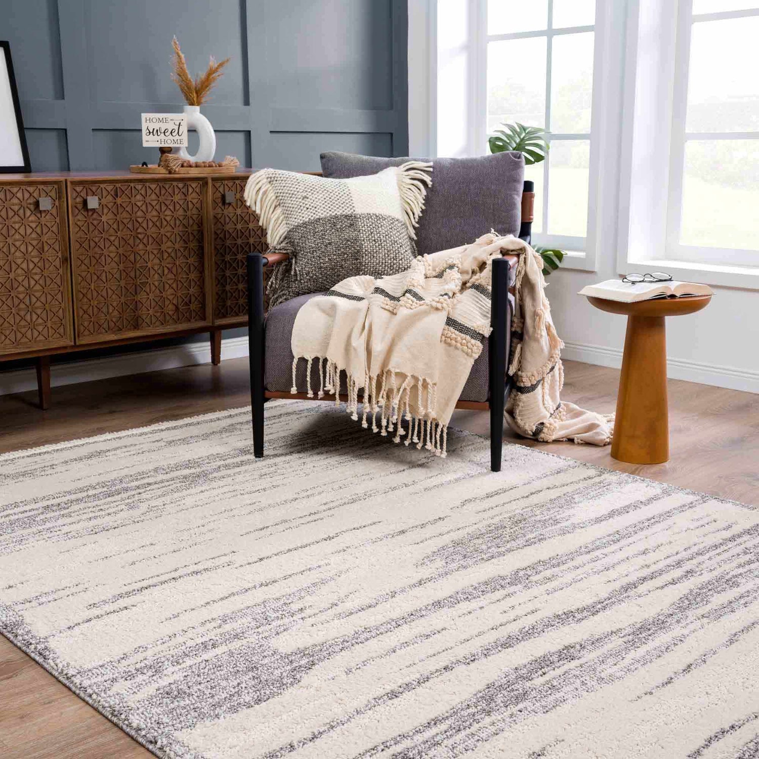Living room scene with Lave Bone & Taupe Area Rug, gray accent chair, wood cabinet, and neutral decor. Roomscene-Rectangle