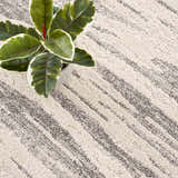 Close-up of Lave Bone & Taupe Area Rug showing texture and striped pattern. Neutral tones. Plant in corner. Styleshot