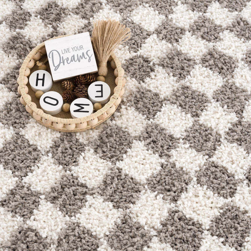 Close-up of the plush Kieu Taupe Checkered Rug. Gray and white geometric pattern with soft, textured shag pile. Styleshot