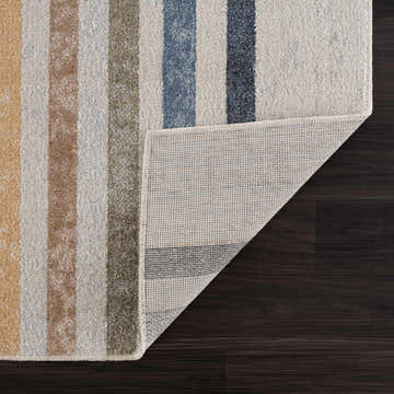 Close-up of Giza Washable Area Rug showing striped design in mustard, tan, blue, and off-white colors and rug backing. Fold