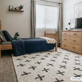 Kids bedroom with a light wood bed and the white Bede Washable Area Rug with black plus sign pattern. Roomscene-Rectangle