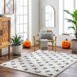 Living room scene with a Bede Washable Area Rug in beige and charcoal, chair, pumpkins, and wood cabinet for Halloween decor. Roomscene-Rectangle