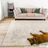 Living room scene with a Binx Thick Luxe Statement Rug in gray, a pink sofa, and a brown dog lying on the rug. Roomscene-Rectangle