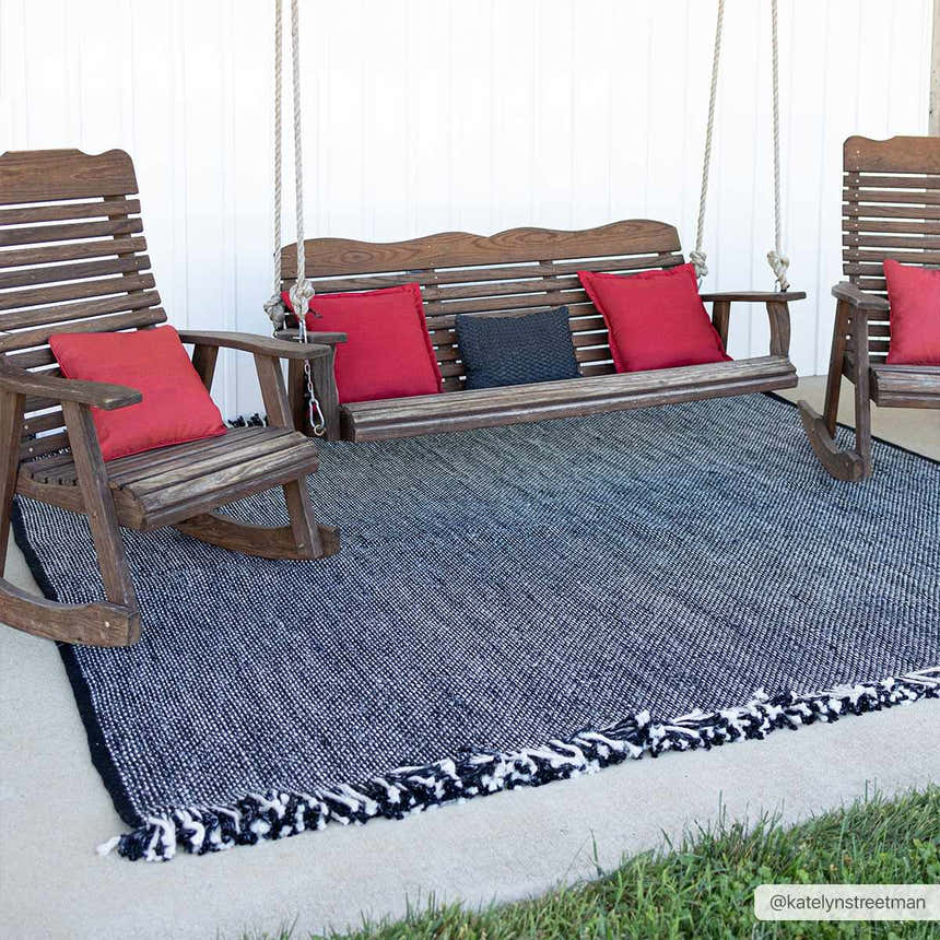 Porch scene with a Boyden Black Area Rug with Tassels under wooden rocking chairs and swing. Red and gray pillows add color. Roomscene-Rectangle