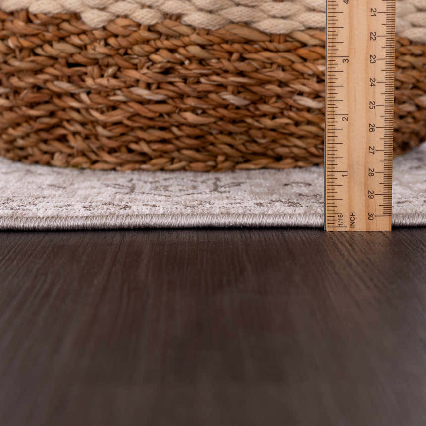 Close-up of the Lugo Luxe Area Rug edge, showing rug thickness with a ruler and a basket detail. Fold
