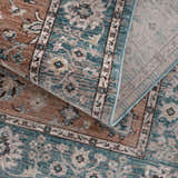 Close-up of the Edremit Area Rug. Traditional oriental pattern in cream, dark blue, dusty pink, and medium brown. Machine woven texture. Fold