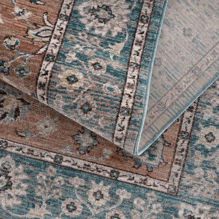 Close-up of the Edremit Area Rug. Traditional oriental pattern in cream, dark blue, dusty pink, and medium brown. Machine woven texture. Fold