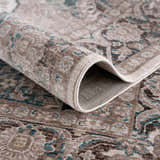 Close-up of the rolled-up Baychester Area Rug. Features a traditional oriental design in cream, brown, and denim blue. Fold