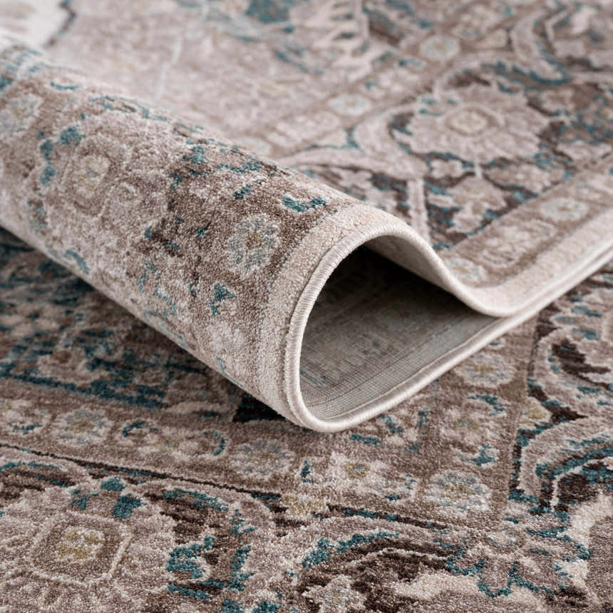 Close-up of the rolled-up Baychester Area Rug. Features a traditional oriental design in cream, brown, and denim blue. Fold