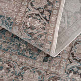 Close-up of the Baychester Area Rug. Features a traditional, oriental design in cream, brown, and denim blue hues. Fold