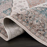Close-up of the rolled Baychester Area Rug, showing its traditional oriental pattern in cream, brown, and denim. Fold