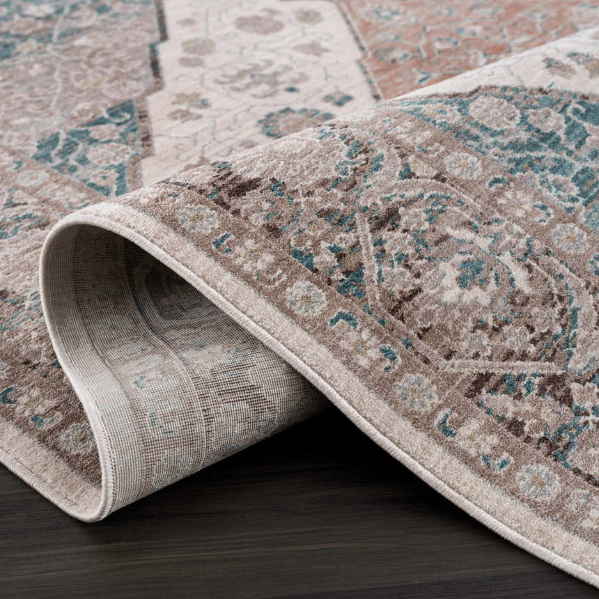 Close-up of the rolled Baychester Area Rug, showing its traditional oriental pattern in cream, brown, and denim. Fold