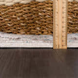 Close-up of the cream and light gray Baychester Area Rug showing pile height with a ruler. Woven basket in background. Pile