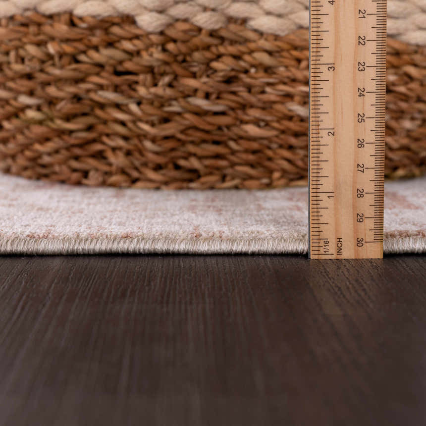 Close-up of the Kaongkod Area Rug edge with a ruler, showing the pile height, and a woven basket. Pile