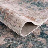 Close-up of the Danlugan Area Rug showing its charcoal, cream, and dusty pink contemporary pattern and soft polyester texture. Fold