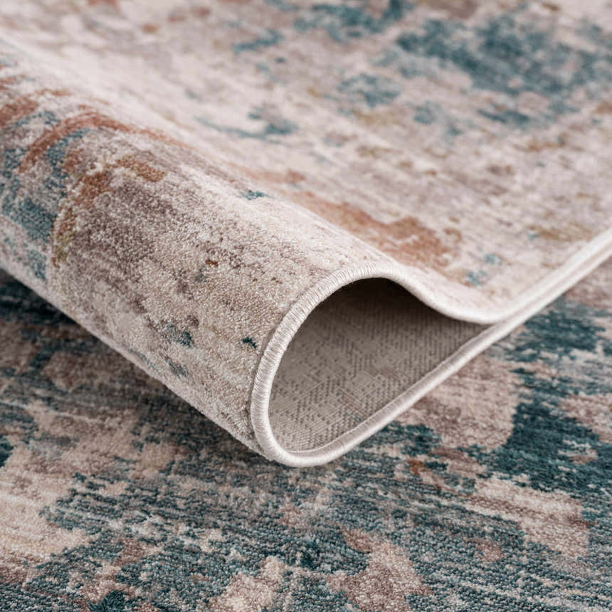Close-up of the Danlugan Area Rug showing its charcoal, cream, and dusty pink contemporary pattern and soft polyester texture. Fold