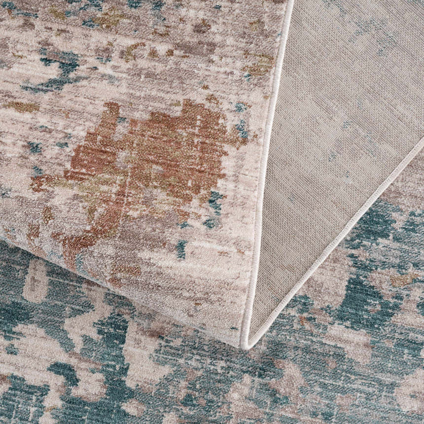 Close-up of the Danlugan Area Rug showing its charcoal, cream, brown, and blue contemporary pattern and polyester texture. Fold