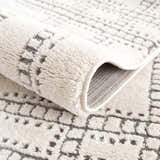 Close-up of the Ryuu Ivory & Gray Area Rug showing its plush texture and geometric pattern in beige and gray tones. Fold