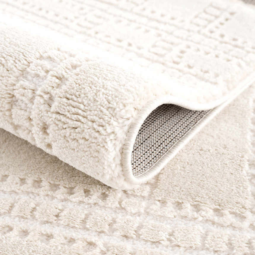 Close-up of the Ryuu Ivory Carved Area Rug showing its plush texture, carved design, and backing. Fold