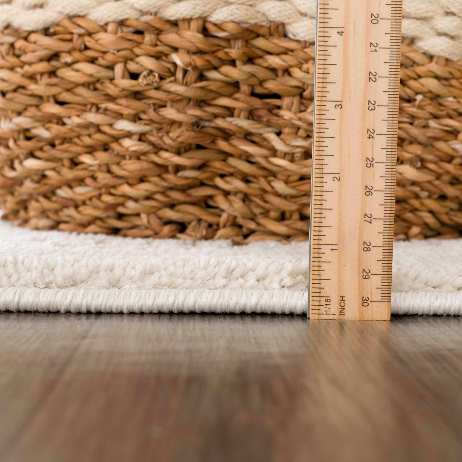 Close-up of the Ryuu Ivory Carved Area Rug showing its plush texture and pile height next to a wooden ruler and woven basket. Pile