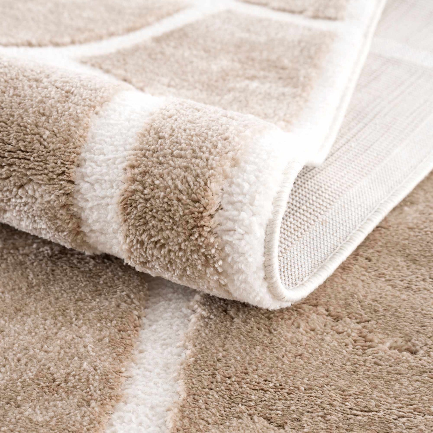 Close up of the plush Azana Cream Area Rug showing its geometric pattern and soft texture. Fold