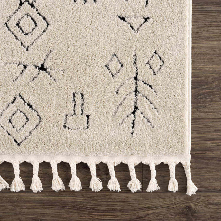 Close up of the Thian Tribal Area Rug showing its beige color, black tribal pattern, and knotted fringe. Corner