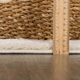 Close-up of Thian Tribal Area Rug pile height, showing beige texture and ruler for scale. Woven basket detail. Pile