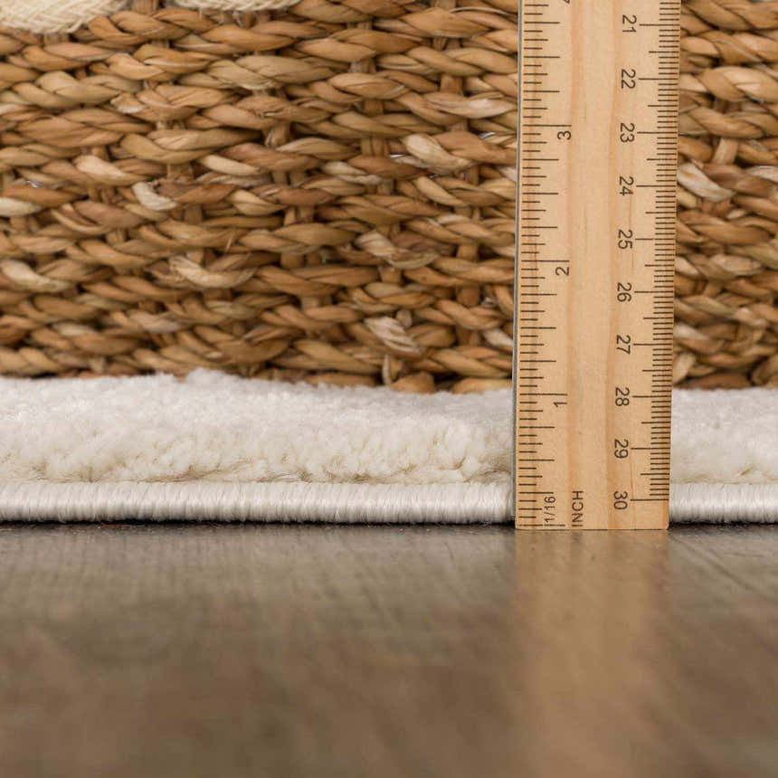 Close-up of Thian Tribal Area Rug pile height, showing beige texture and ruler for scale. Woven basket detail. Pile