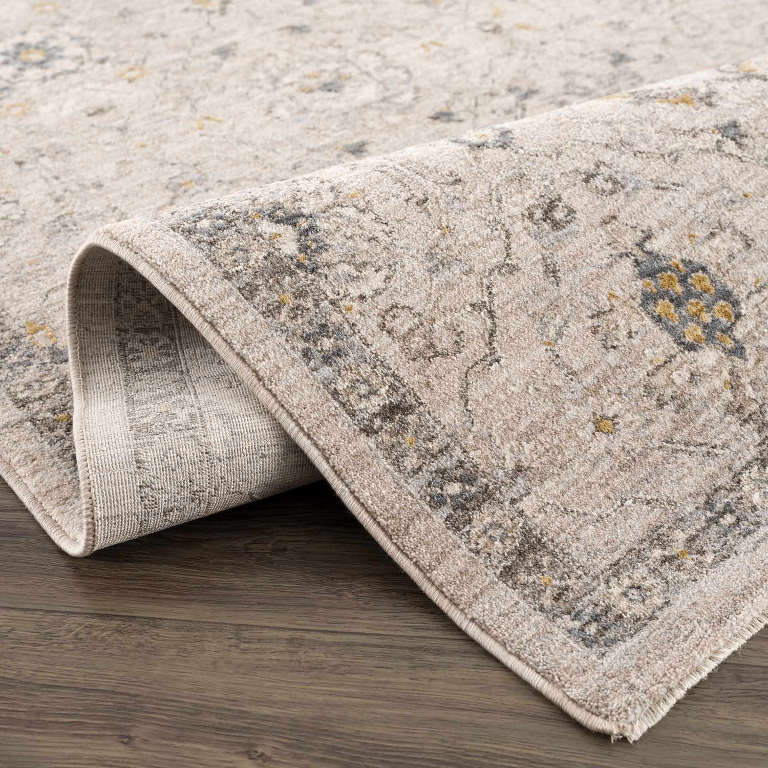 Close up of the Annie Cream Textured Rug showing its traditional pattern and soft, neutral colors. Fold