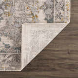 Close-up of the Alroy Textured Rug with Fringes showing its gray, brown, and gold floral pattern and textured weave. Fold