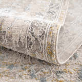 Close-up of the Alroy Textured Rug, showcasing its gray, brown, and gold tones and intricate traditional pattern. Fold