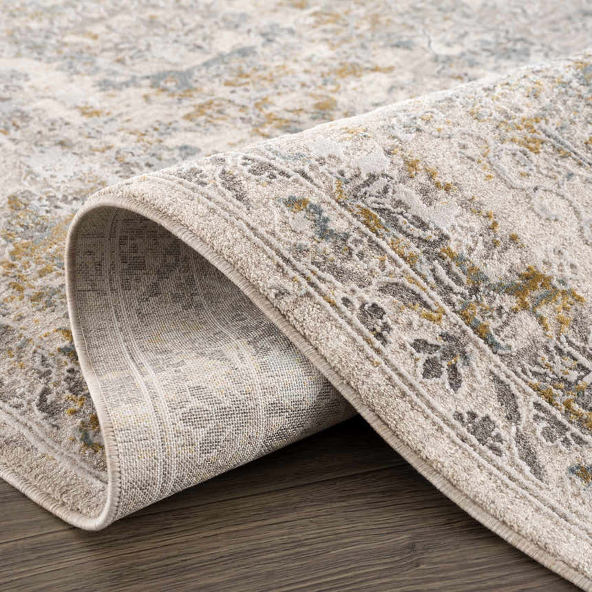 Close-up of Alroy Textured Rug with Fringes. Features gray, light gray, and gold floral pattern. Shows rug's texture. Fold