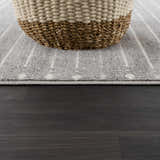 Close-up of Tigri Aztec Ivory & Gray Area Rug with a basket. Gray rug has a subtle stripe pattern. Pile