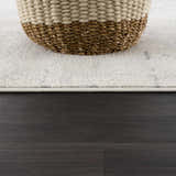 Close-up of the Tigrima Ivory 2319 area rug showing its subtle pattern and texture next to a woven basket. Styleshot