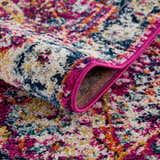 Close-up of the New Vick Area Rug, a machine-woven runner with a colorful farmhouse pattern in pink, blue, yellow, and white. Fold