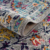 Close-up of the New Delanson Area Rug featuring a gray, floral pattern with accents of blue, pink, and yellow. Fold