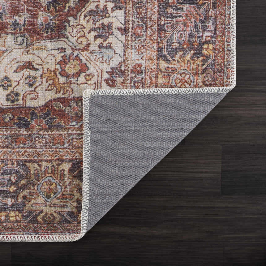 Close up of the Rust Elki Vintage Medallion Washable Area Rug showing its rust, blue, and off-white Persian-style pattern. Fold