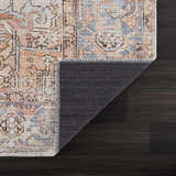 Close-up of the Eira Distressed Washable Rug showing charcoal, light blue, orange, and red Persian-style pattern. Fold