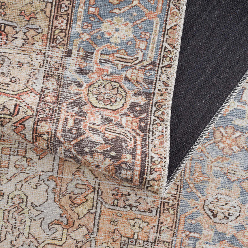 Close-up of the Eira Distressed Washable Rug showing its charcoal, blue, orange, and off-white Persian-style pattern. Fold