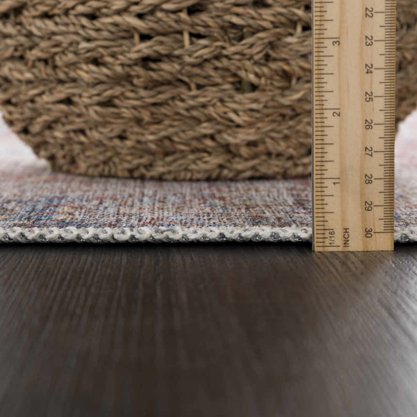 Close-up of the Rust Elki Vintage Medallion Washable Area Rug showing the rug's thickness with a ruler. Pile