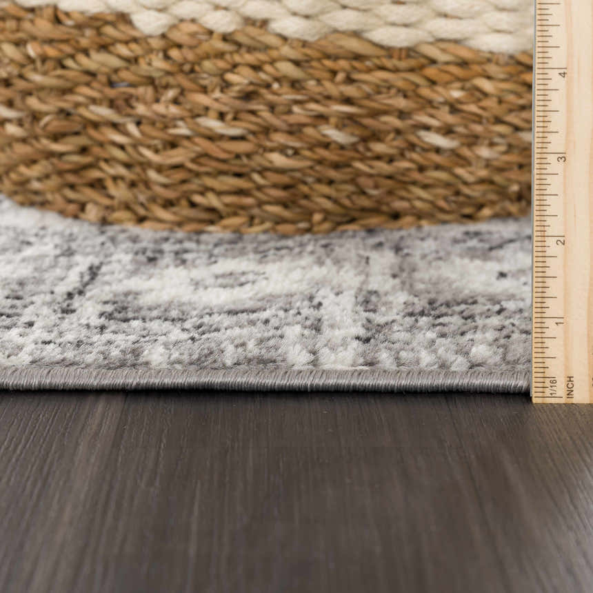 Close-up of the Marash 4605 Gray Area Carpet showing the rug's edge, gray, ivory, and silver gray colors, and a ruler for scale. Pile