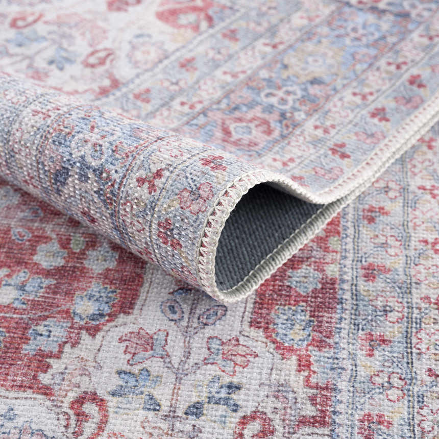 Close-up of the Rust Goma Vintage Area Rug showing its blush, cream, and blue traditional floral pattern and machine-woven texture. Fold