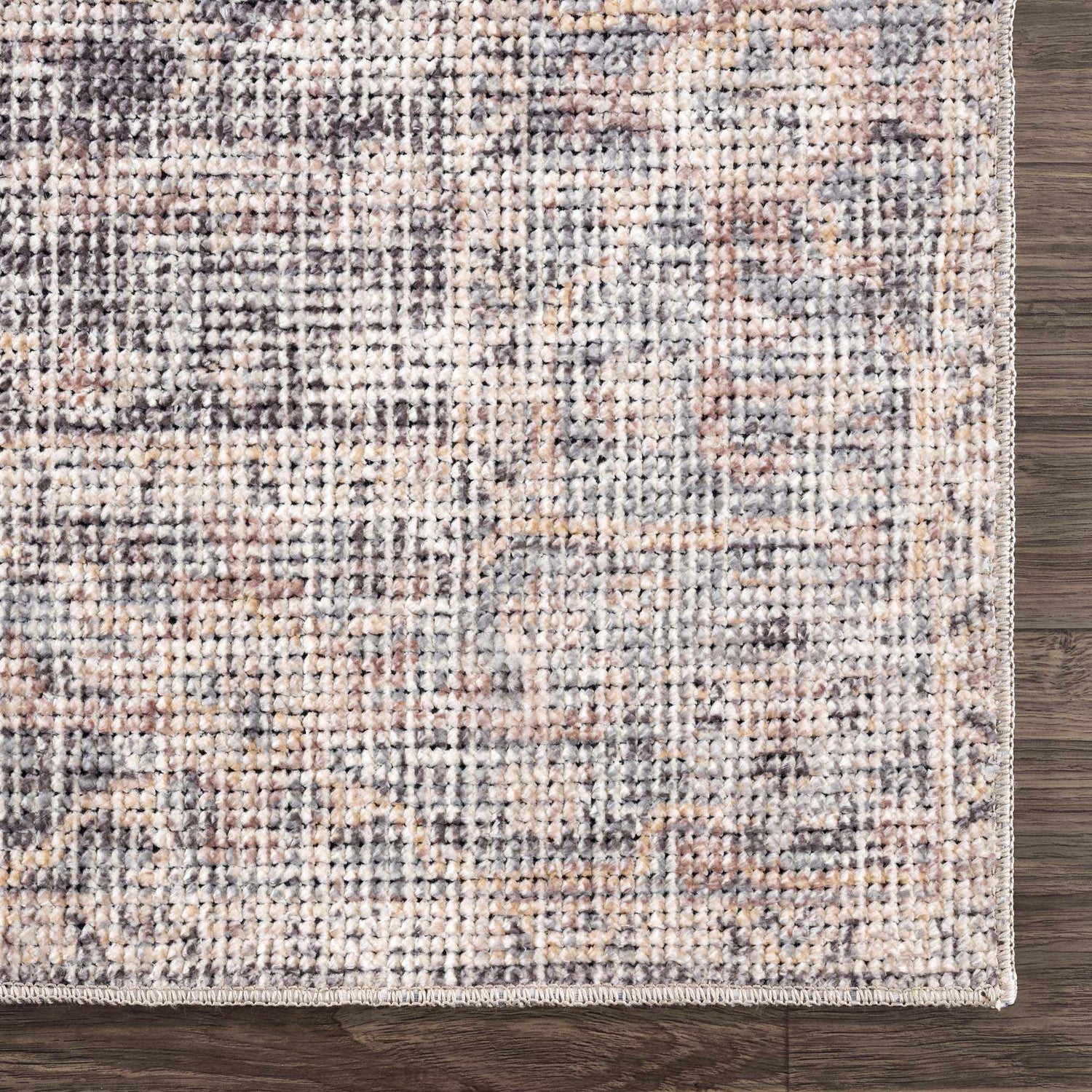 Close-up of the Nyota Area Rug. Traditional vintage style with gray, beige, and brown tones. Machine-woven texture. Corner