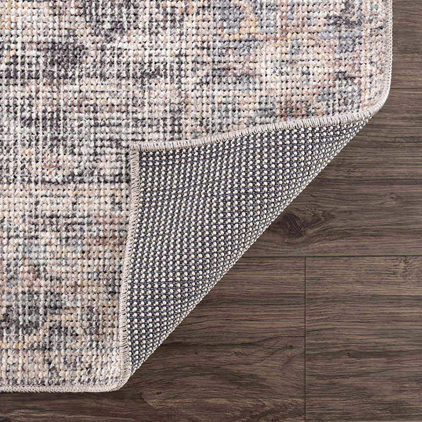 Close-up of Nyota Area Rug showing vintage pattern, neutral colors, and durable woven backing on dark wood floor. Fold