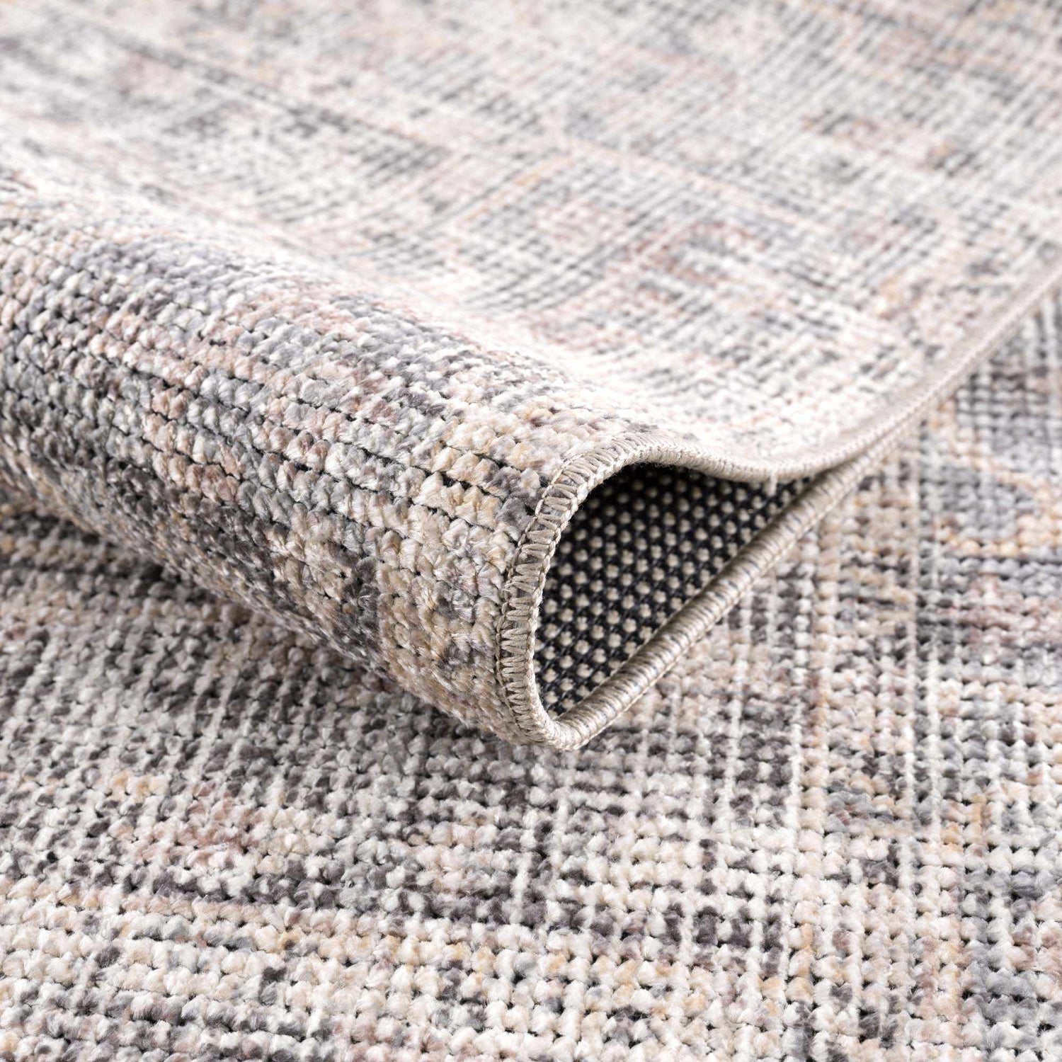 Close-up of the Nyota Area Rug showing its vintage traditional design, soft texture, and neutral gray, beige, and brown tones. Fold