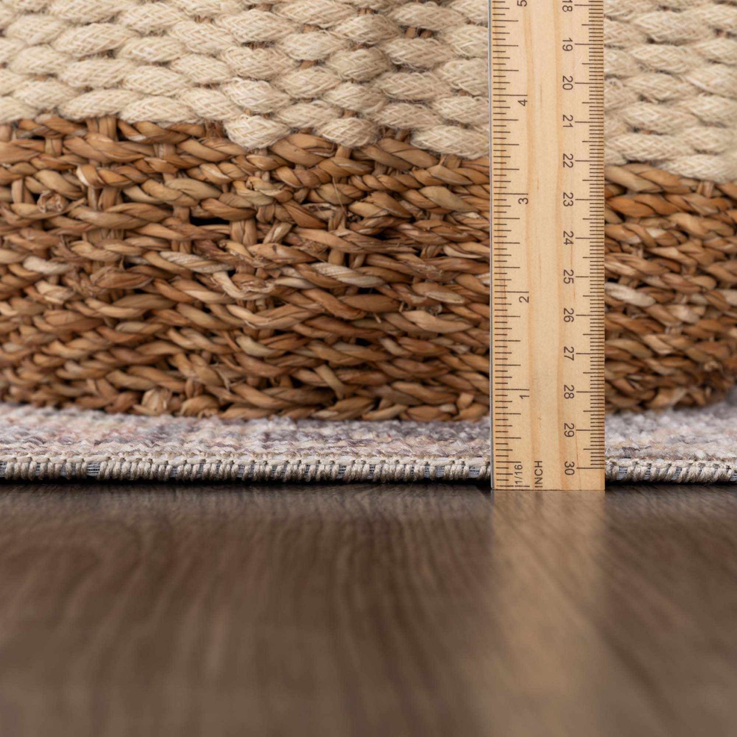 Close-up of the Nyota Area Rug showing its texture and pile height next to a ruler and woven basket. Pile